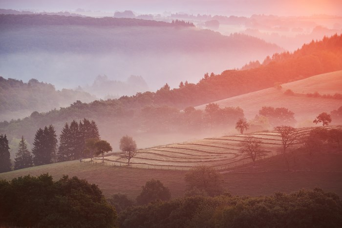 Misty hills at sunrise with colorful haze