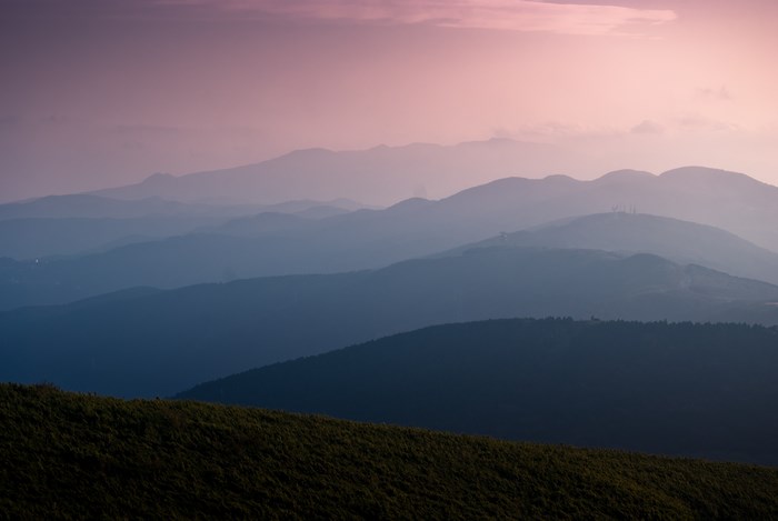 Layered mountains at sunset with pink sky