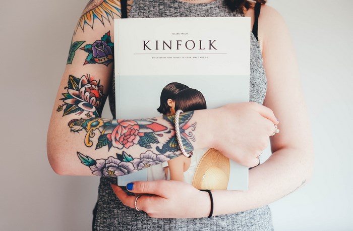 Woman with tattoos holding Kinfolk magazine
