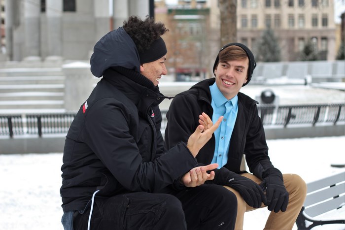 Two young men talking on a bench in the snow