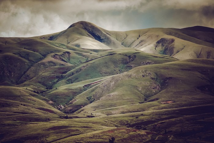 Green rolling hills and mountains under a cloudy sky
