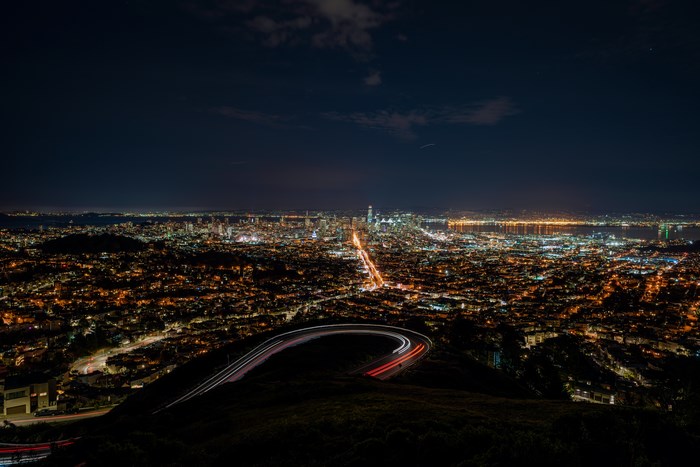 San Francisco cityscape at night with light trails on a winding road