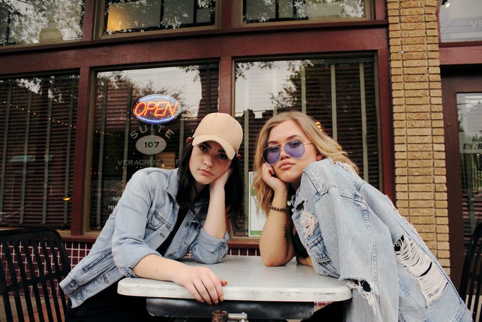 Two young women sitting at a table outside a cafe