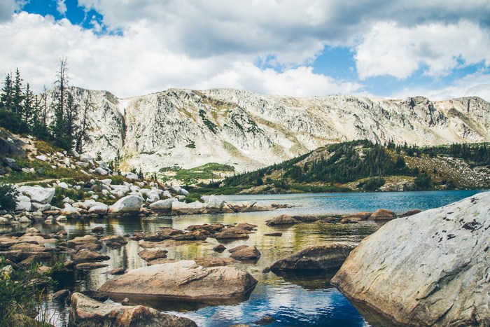 Rocky mountain lake with white granite peaks and clouds