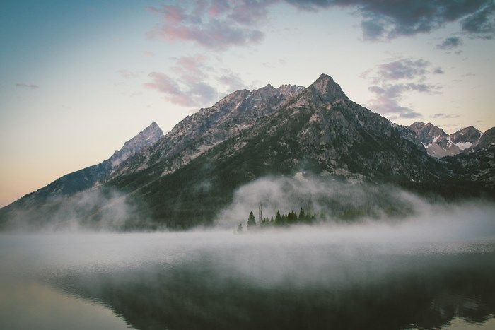 Misty mountain lake at sunrise with reflection