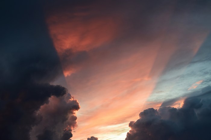 Dark and pink clouds at sunset with rays of light