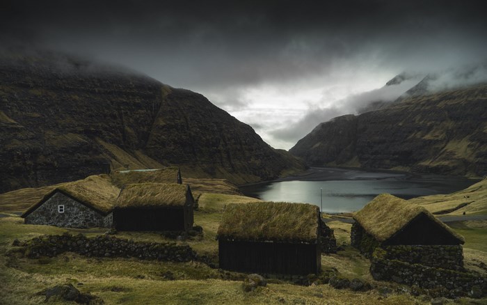 Moody landscape with grass-roofed huts and a lake