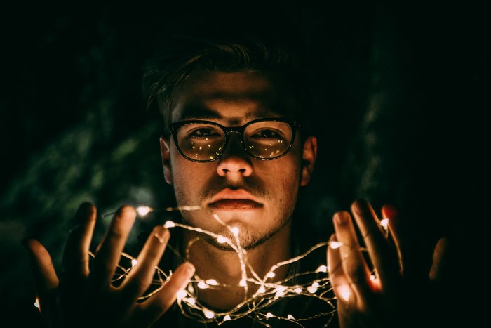 Man wearing glasses holding fairy lights