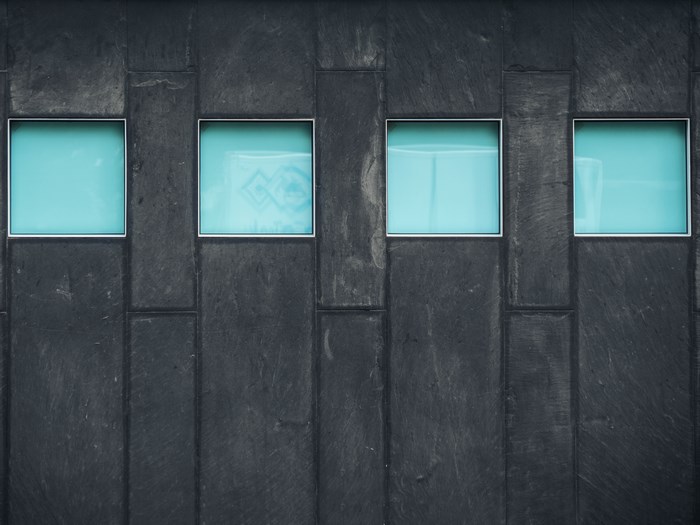 Four blue windows on a dark stone facade