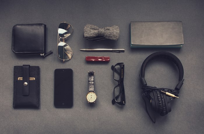Flatlay of men's accessories including wallet, phone, and watch