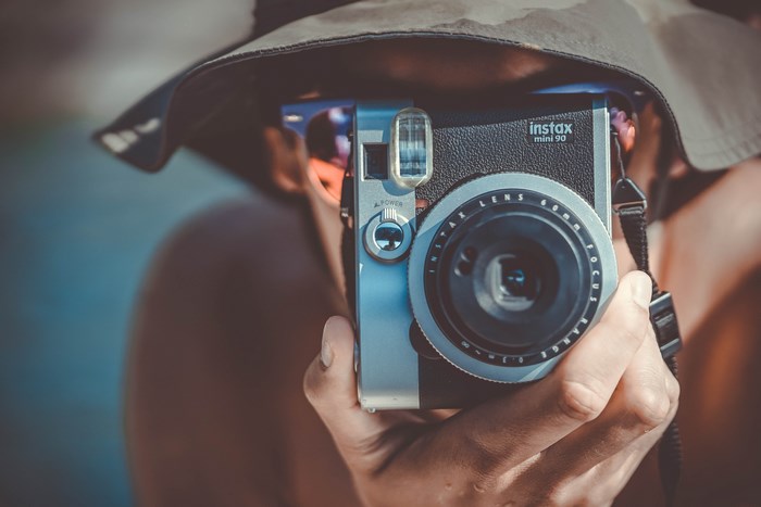 Person holding an Instax Mini 90 camera