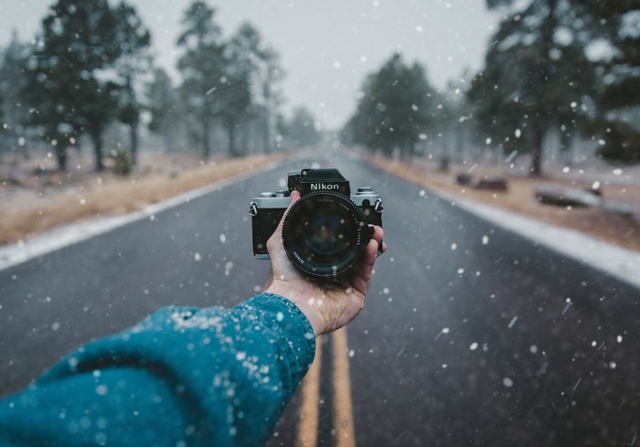 Person holding a Nikon camera on a snowy road