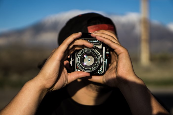Man holding a Mamiya 645 camera in front of a mountain