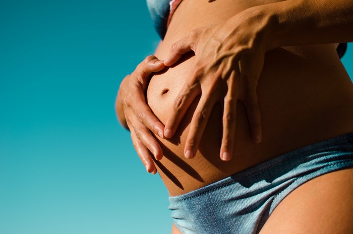 Pregnant woman forming a heart shape on her belly
