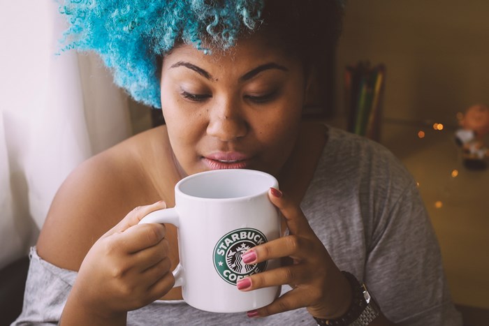 Woman with blue hair holding a Starbucks mug