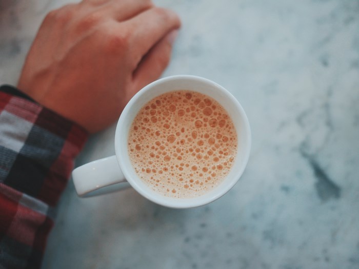 Hand holding a cup of coffee with foam