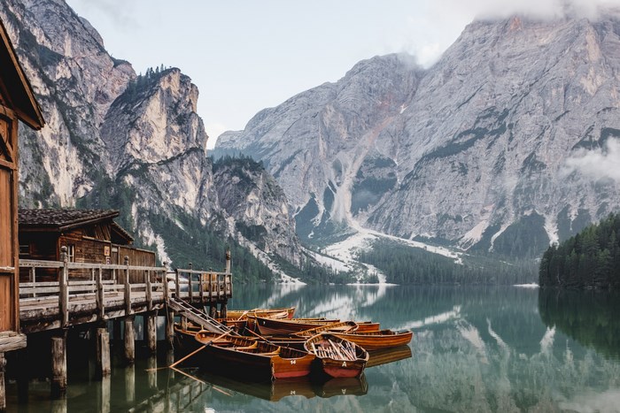 Wooden boats moored at a dock on a lake with mountains