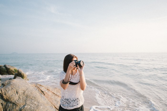 Woman taking a photo on the beach with a camera