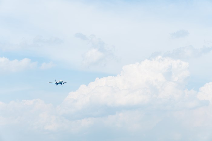 Airplane flying in a pastel blue sky with clouds