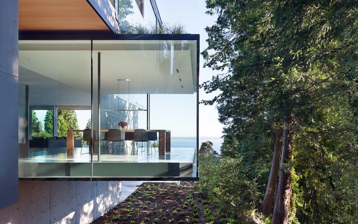 Modern glass house with dining room overlooking water