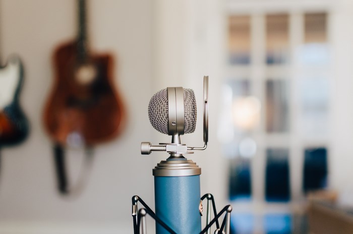 Blue studio microphone with guitars in background