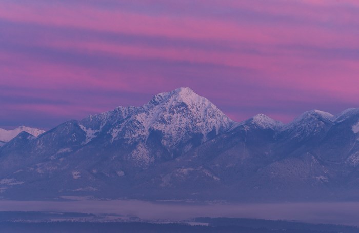 Snow-covered mountains at sunrise with pink sky