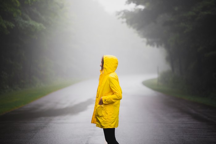 Woman in yellow raincoat on foggy road in Quebec