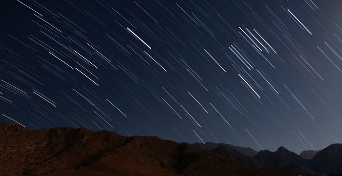 Starry night sky over a desert mountain landscape