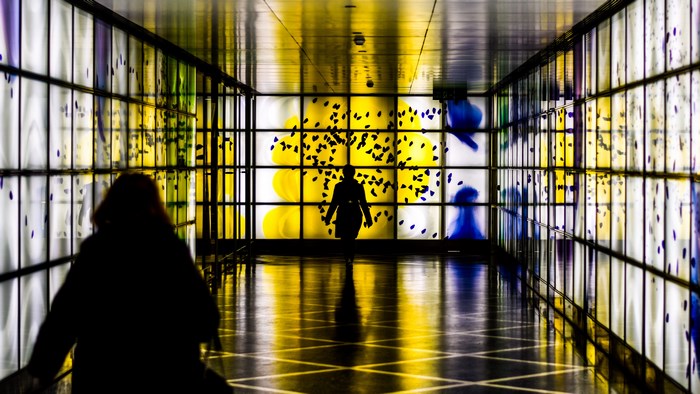 People walking through a brightly lit modern corridor with glowing panels