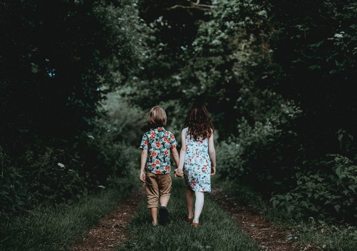 Boy and girl holding hands walking in a forest