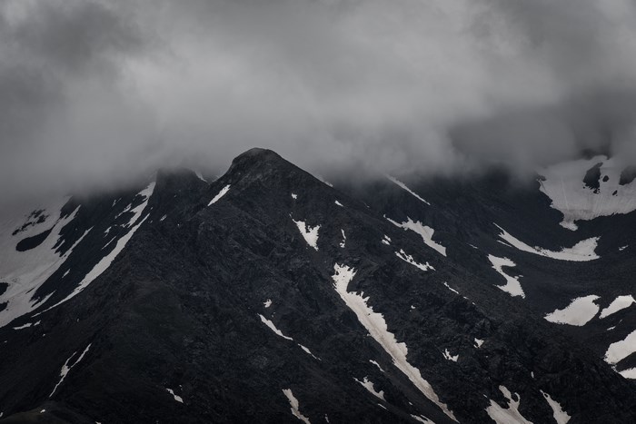 Dark mountain peak with snow under overcast sky