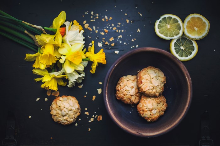 Daffodils, cookies, and lemon slices on a dark surface