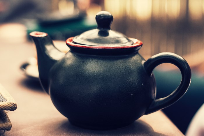 Black ceramic teapot with red trim on a table