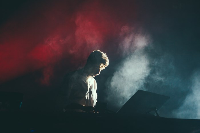 Man performing on stage with red and white smoke