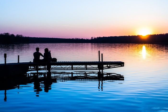 Couple on a dock watching the sunset over a lake