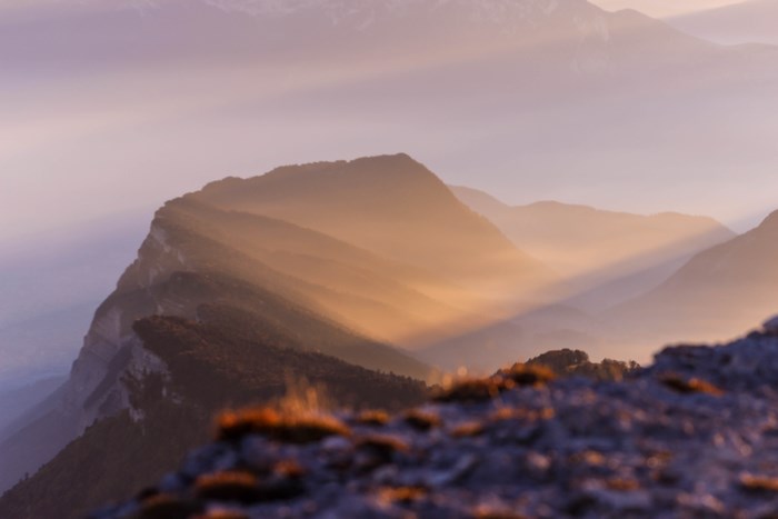 Sunlight streams through misty mountain ridges at dawn