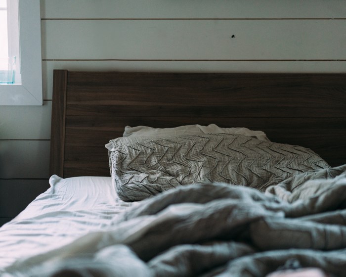 Cozy bedroom with a rumpled duvet and pillow on a bed