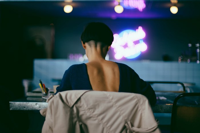 Woman with short hair at a table with neon lights