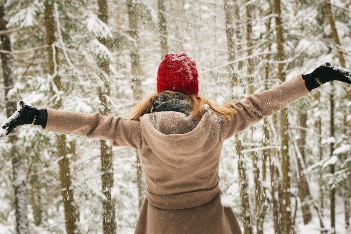 Woman in red hat enjoying snowfall in forest