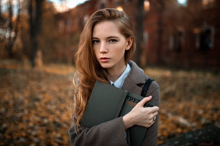 Redhead girl with freckles holding books