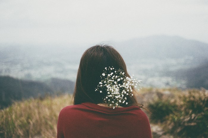 Woman with flower in hair on foggy mountain