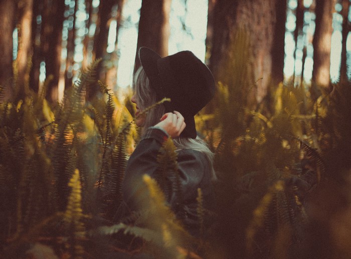 Woman wearing a hat in a forest with ferns