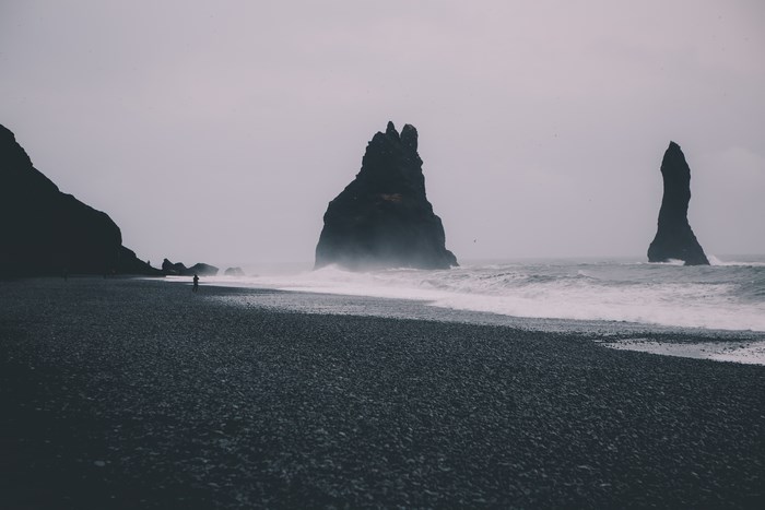 Black sand beach with rock formations and waves
