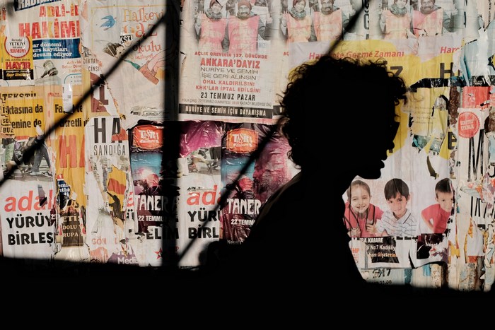 Silhouette against posters with children and protest slogans
