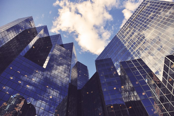 Modern glass skyscrapers reflecting the sky and clouds
