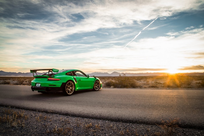 Green Porsche 911 GT3 on a desert road at sunset