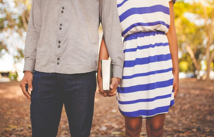 Couple holding a book and hands outdoors