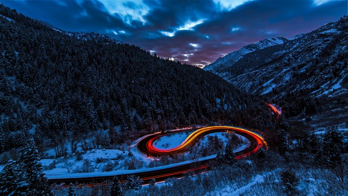Long exposure of a winding mountain road at night in winter