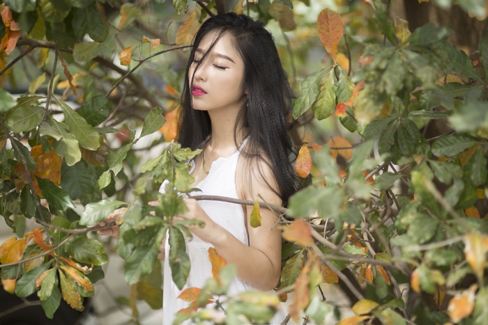 Serene Woman with Long Black Hair Among Autumn Leaves