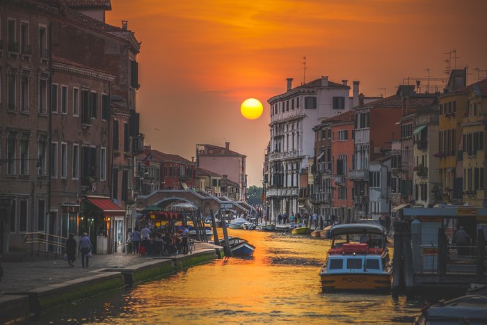 Venice canal at sunset with boats and buildings